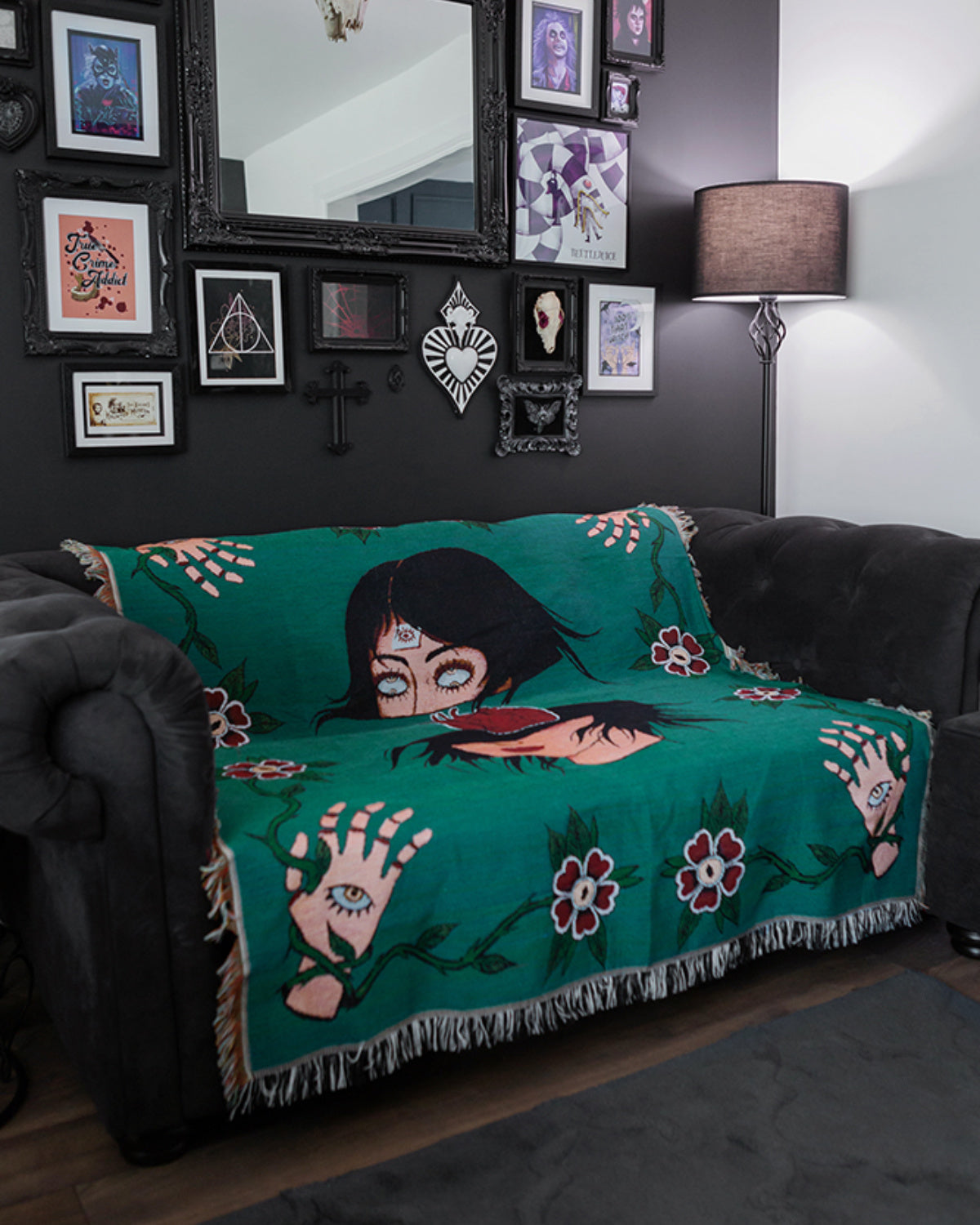 Teal blanket with artistic design on a black couch in a room with framed pictures on the wall.