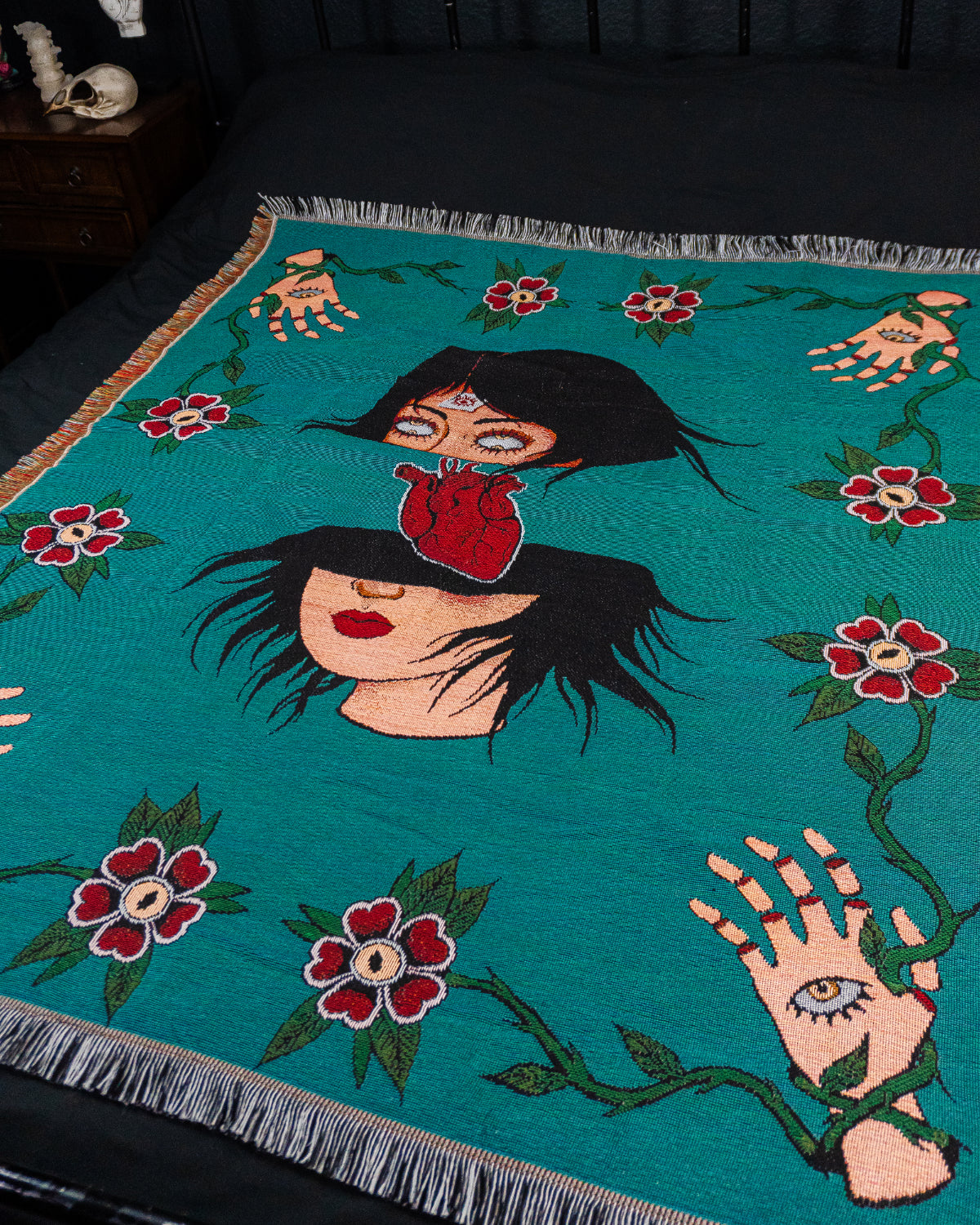 Decorative blanket with artistic design of a woman, flowers, and hands on a teal background.