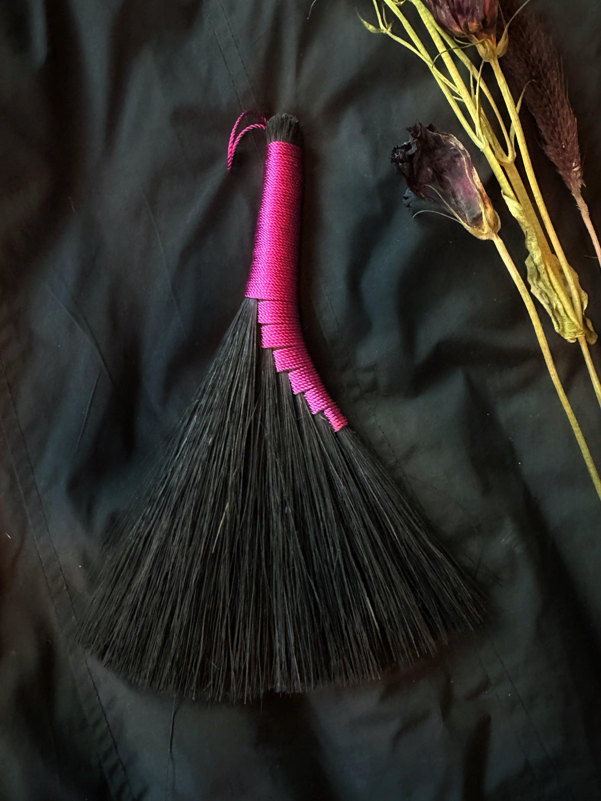 Broom with pink handle on a dark surface