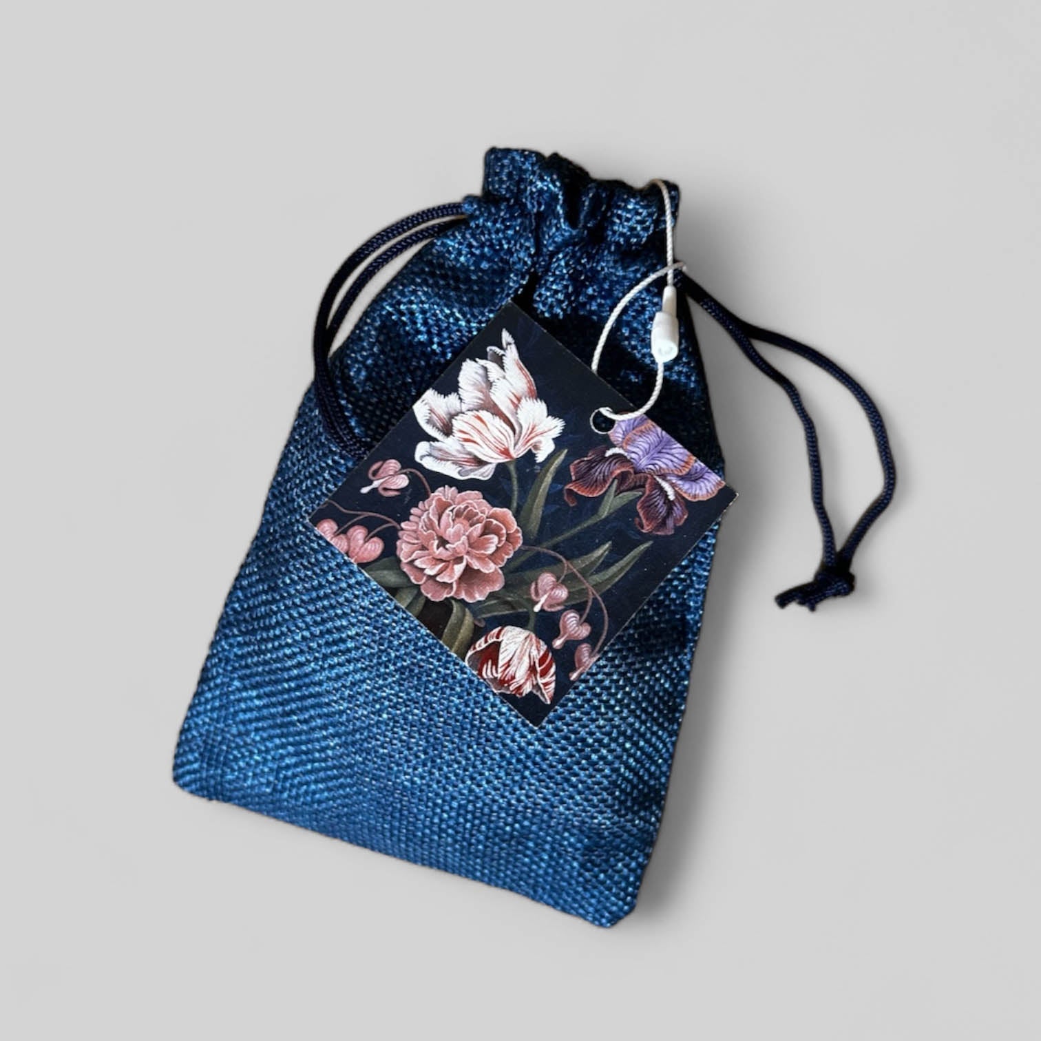 Blue drawstring pouch with a floral tag on a light gray background
