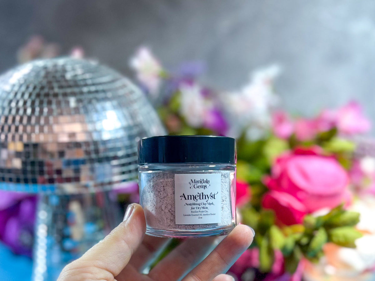 Hand holding a jar of 'Amethyst' powder with disco ball and flowers in the background