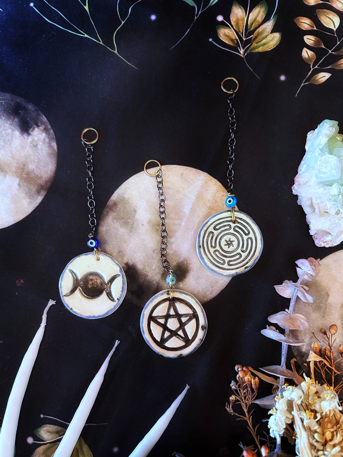Handmade porcelain wall hanging to decorate your home. They are made in symbols of the hecate wheel, a pentacle, or the triple moon. There is a small evil eye glaze bead with a chain and a hanging loop.