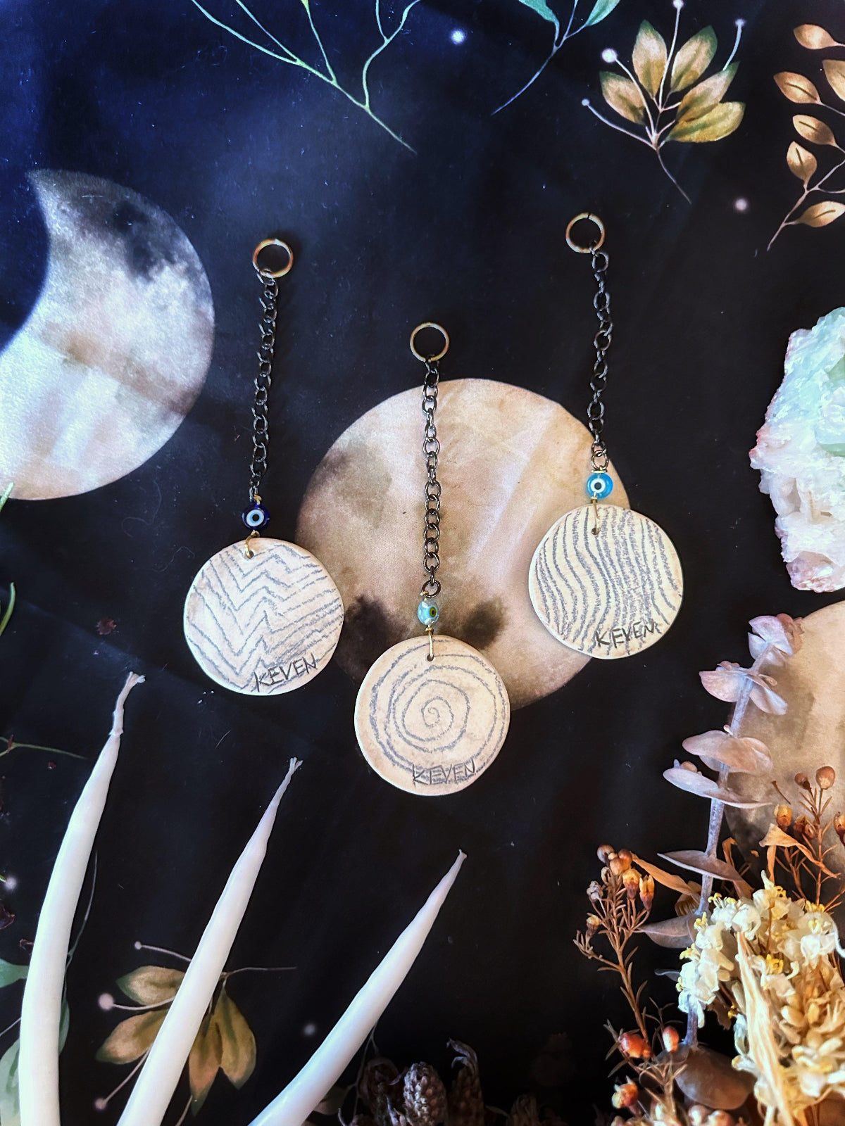 Handmade porcelain wall hanging to decorate your home. They are made in symbols of the hecate wheel, a pentacle, or the triple moon. The is the back size with an abstract drawn shape. There is a small evil eye glaze bead with a chain and a hanging loop.